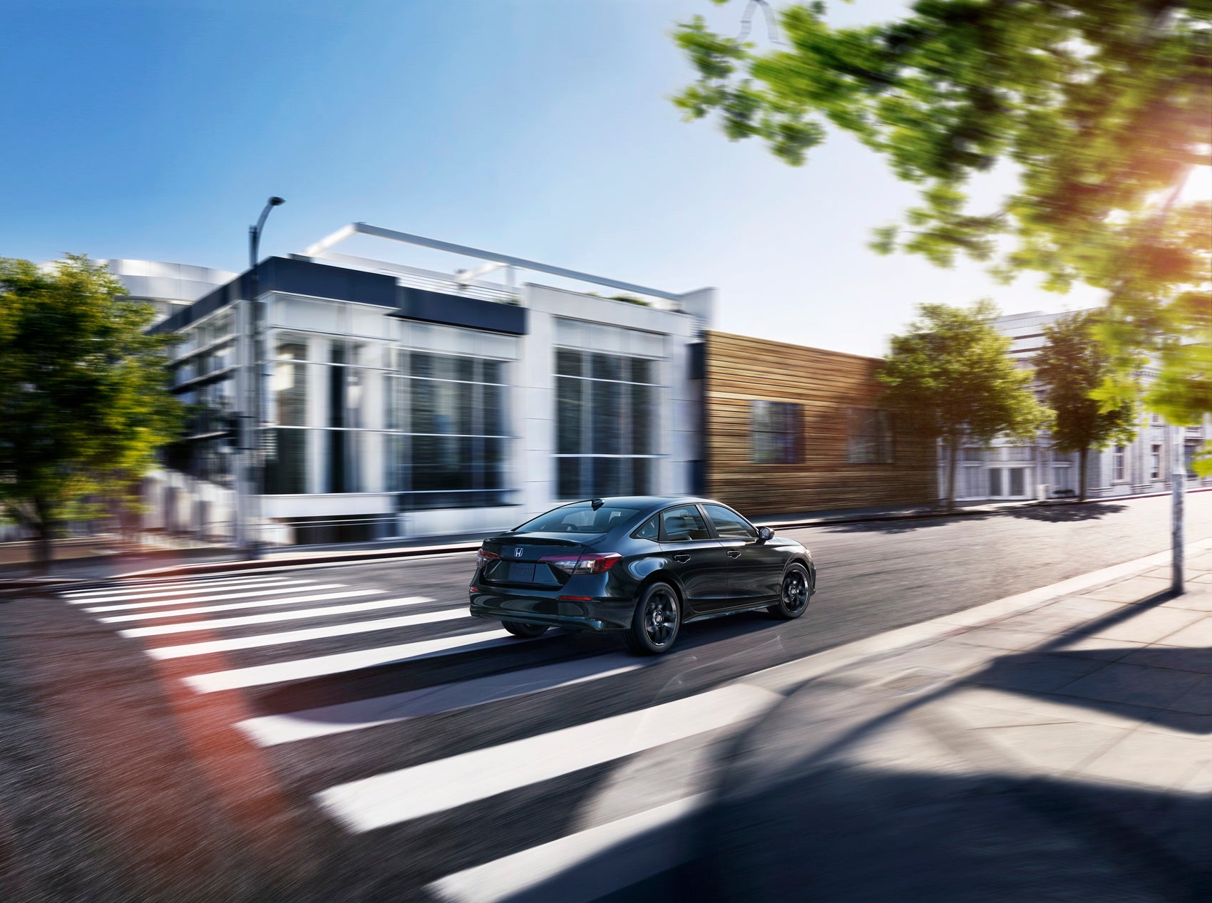 Black Honda Civic driving through downtown Lawrence NJ on a sunny day